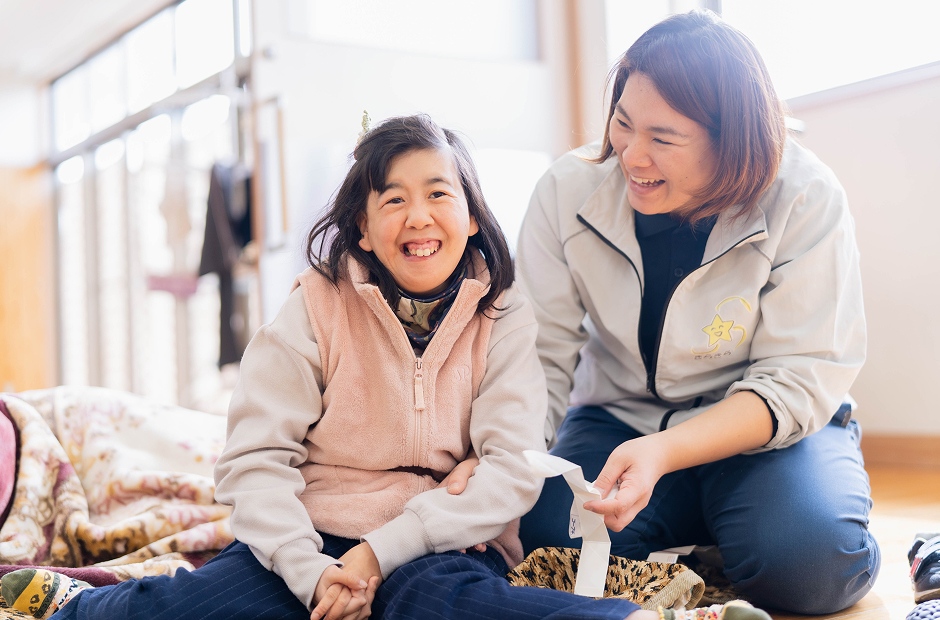 職員と入居者が一緒に笑顔で過ごす生活風景。居間での交流の様子。